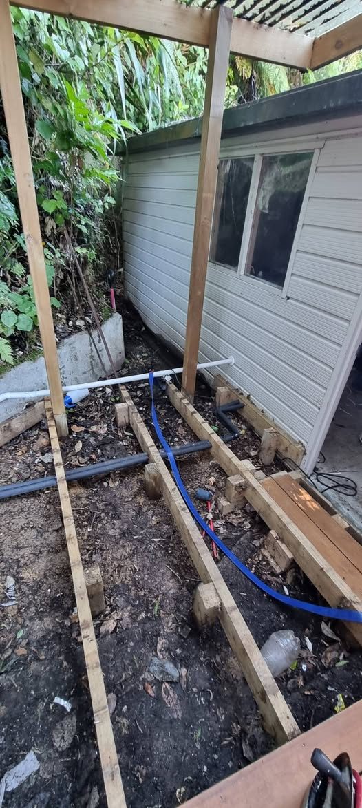 Drainlayer at work on an Upper Hutt property — earthenware drain section exposed during repair
